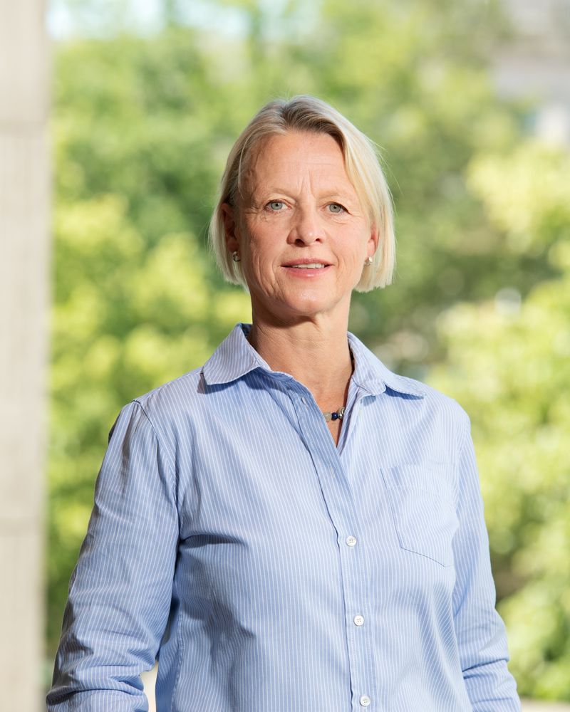 Porträt von Dr. Tenna Dahl in einer hellblauen Bluse vor grünem Hintergrund